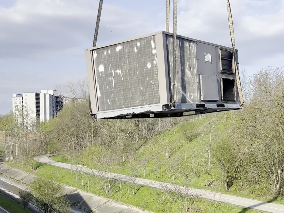 Crane lifting old commercial rooftop unit off a flat roof in Kitchener-Waterloo